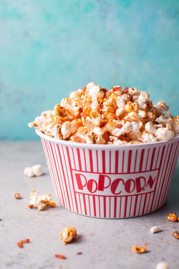 bowl of sriracha bacon popcorn on a blue background