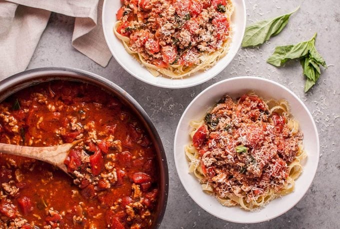 skillet and two white bowls with turkey bolognese