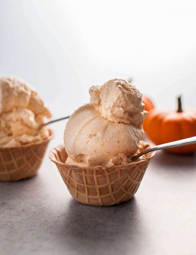 two ice cream cone cups with homemade cinnamon pumpkin ice cream and spoons
