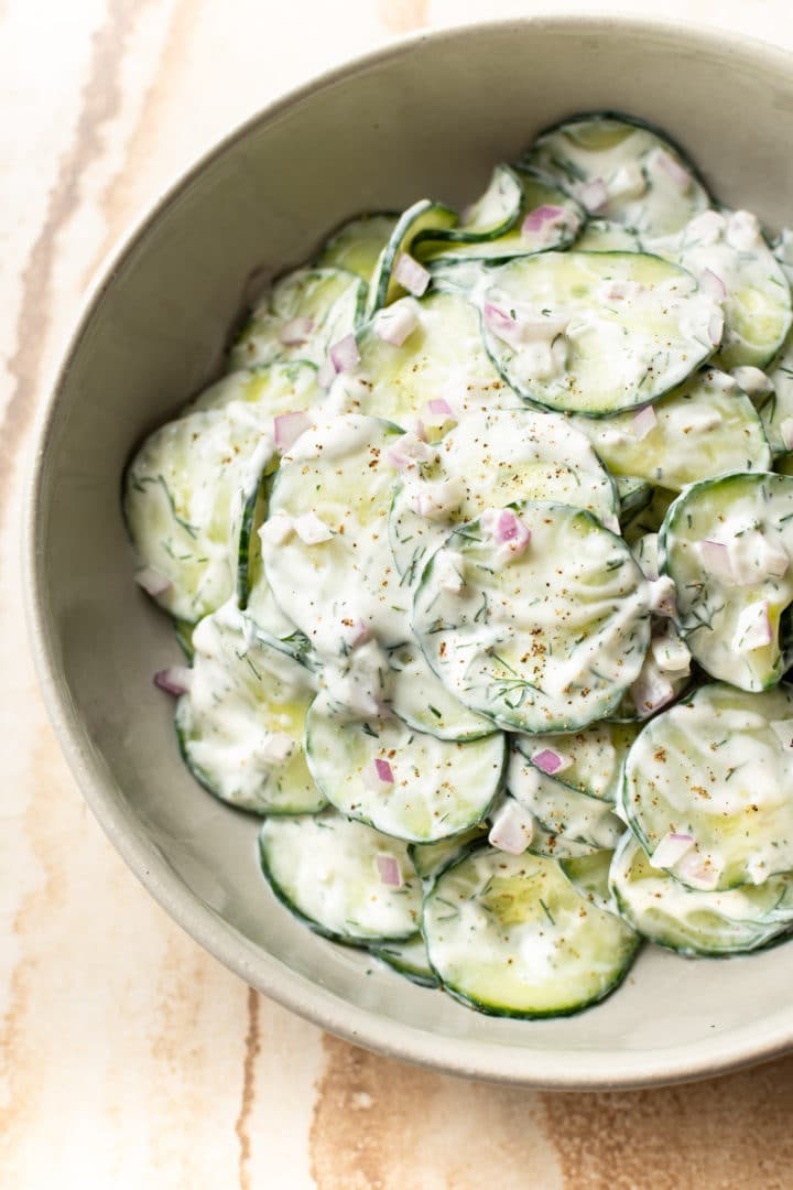 the BEST creamy cucumber salad (close-up in beige serving bowl)