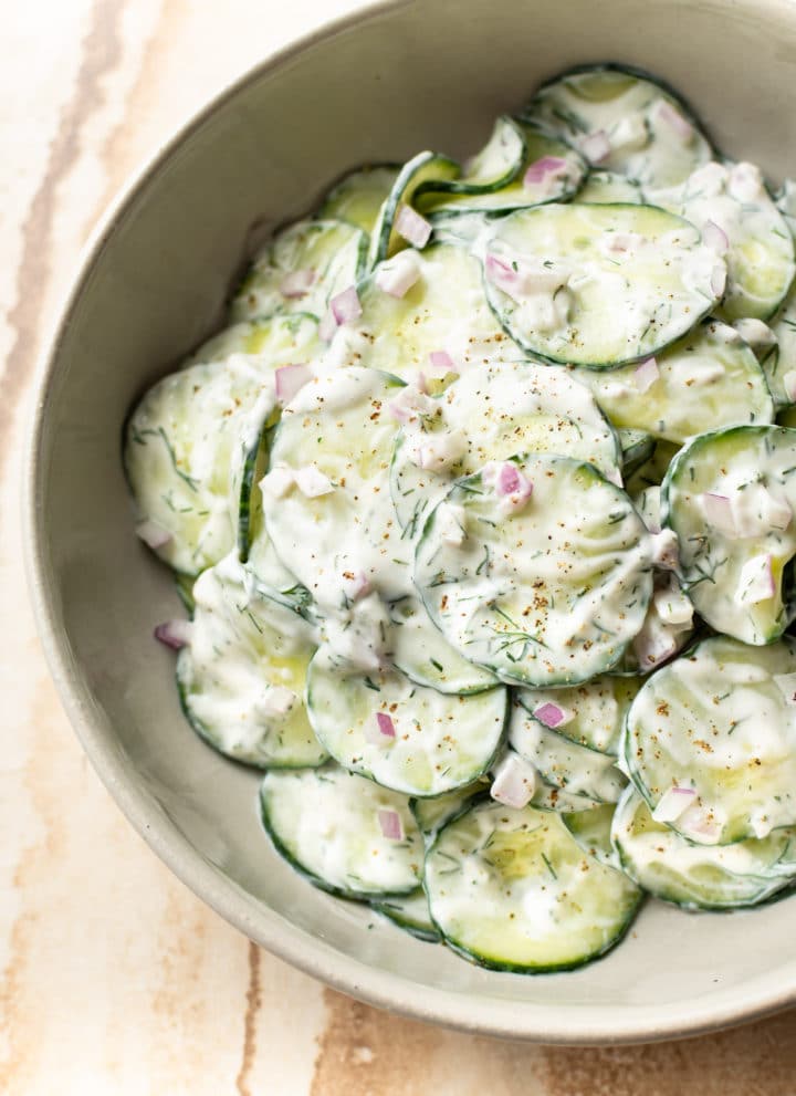 the BEST creamy cucumber salad (close-up in beige serving bowl)