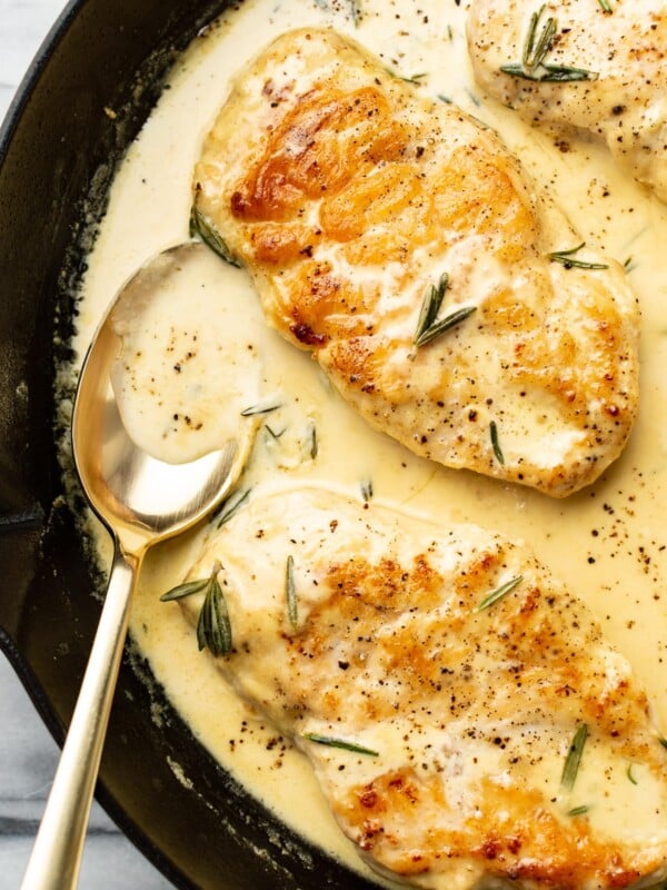 closeup of rosemary dijon chicken in a skillet with a serving spoon