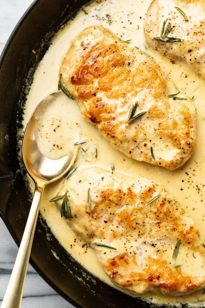 closeup of rosemary dijon chicken in a skillet with a serving spoon