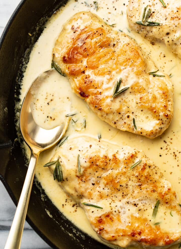 closeup of rosemary dijon chicken in a skillet with a serving spoon