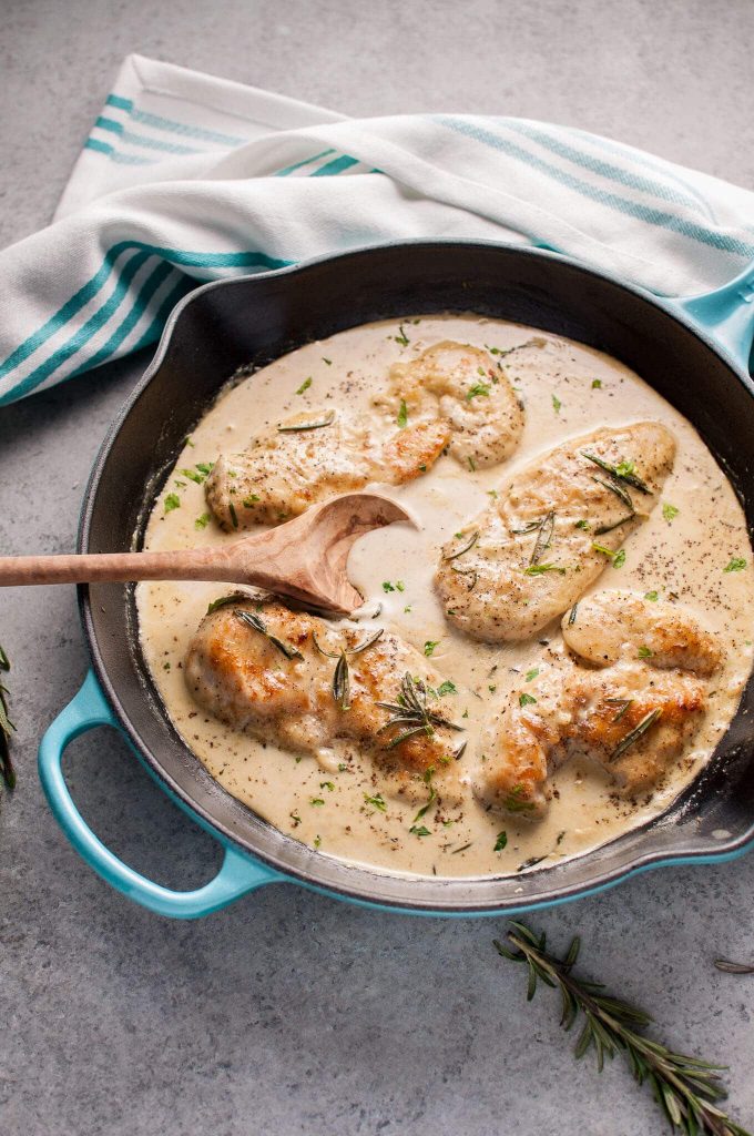 easy creamy rosemary Dijon chicken in a skillet with wooden cooking spoon
