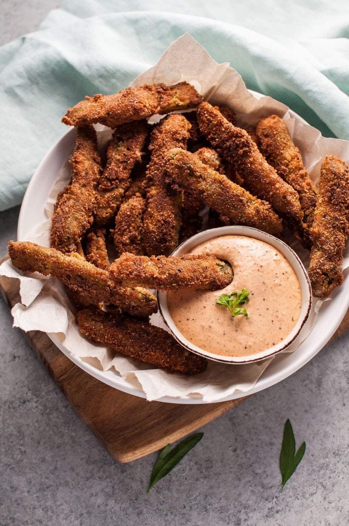 several fried pickles with remoulade sauce in a bowl