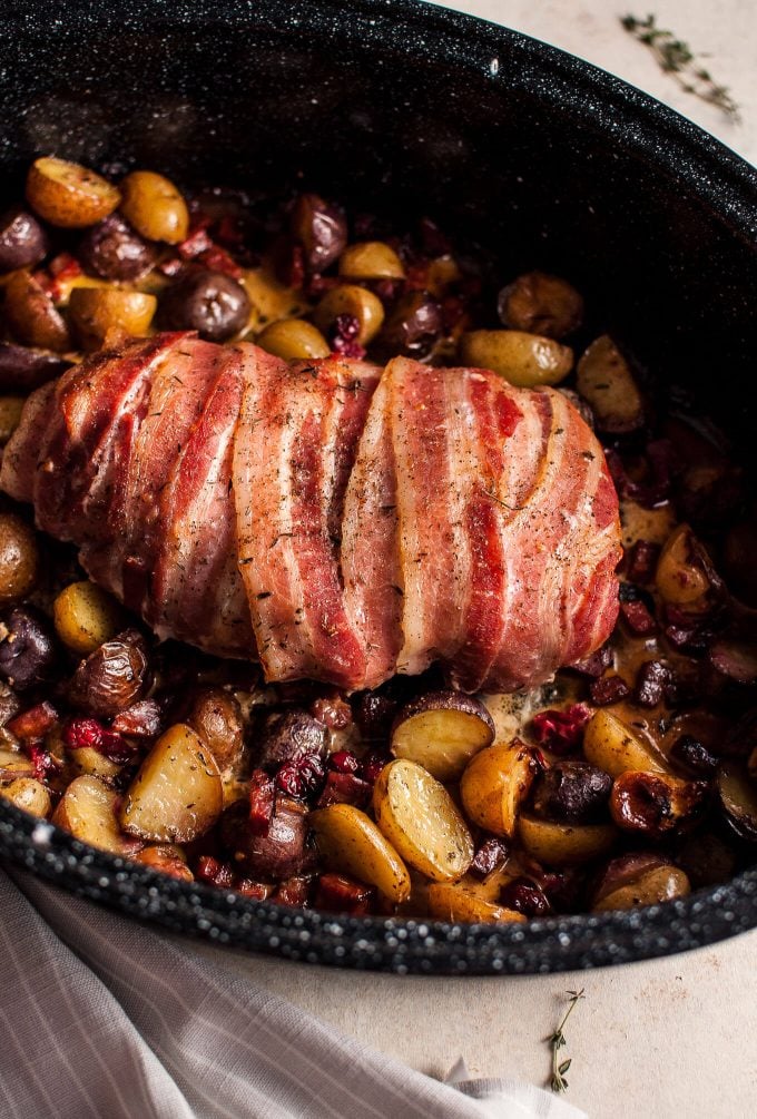 bacon-wrapped turkey breast with chorizo, cranberries, and little potatoes in a roasting pan close-up