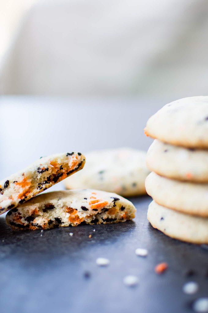 close up of vegan Halloween cookie broken in half beside stack of cookies