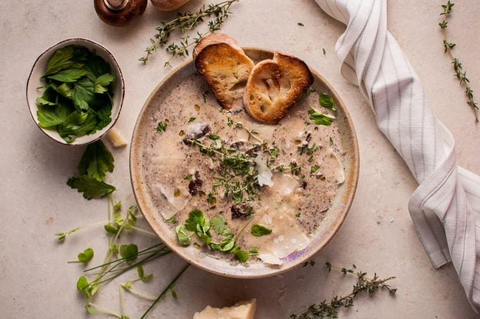 bowl of loaded creamy mushroom soup with toasted baguette and parmesan
