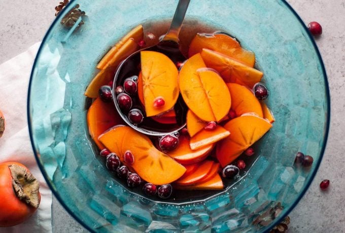 a blue punch bowl with winter pomegranate and persimmon sangria and a spoon