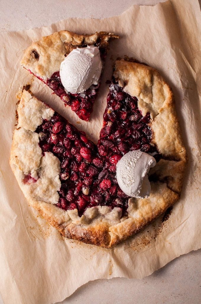 rustic cranberry galette on parchment paper with two scoops of ice cream