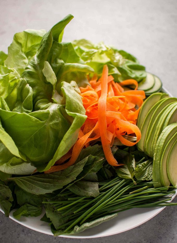 lettuce, carrots, cucumber, and sliced avocado on a plate