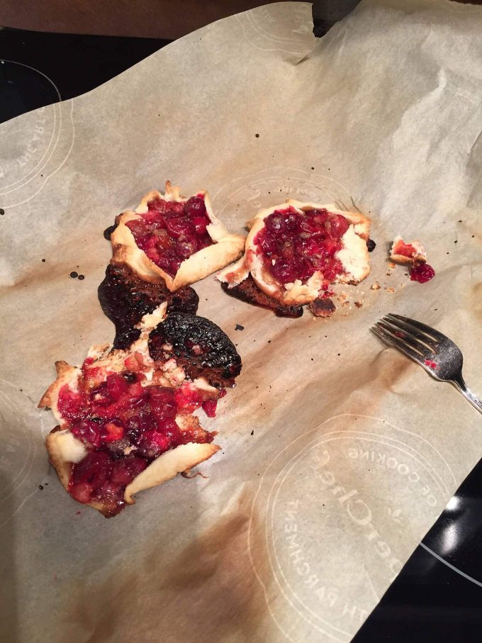 three not good looking mini cranberry galettes on parchment paper with burnt edges