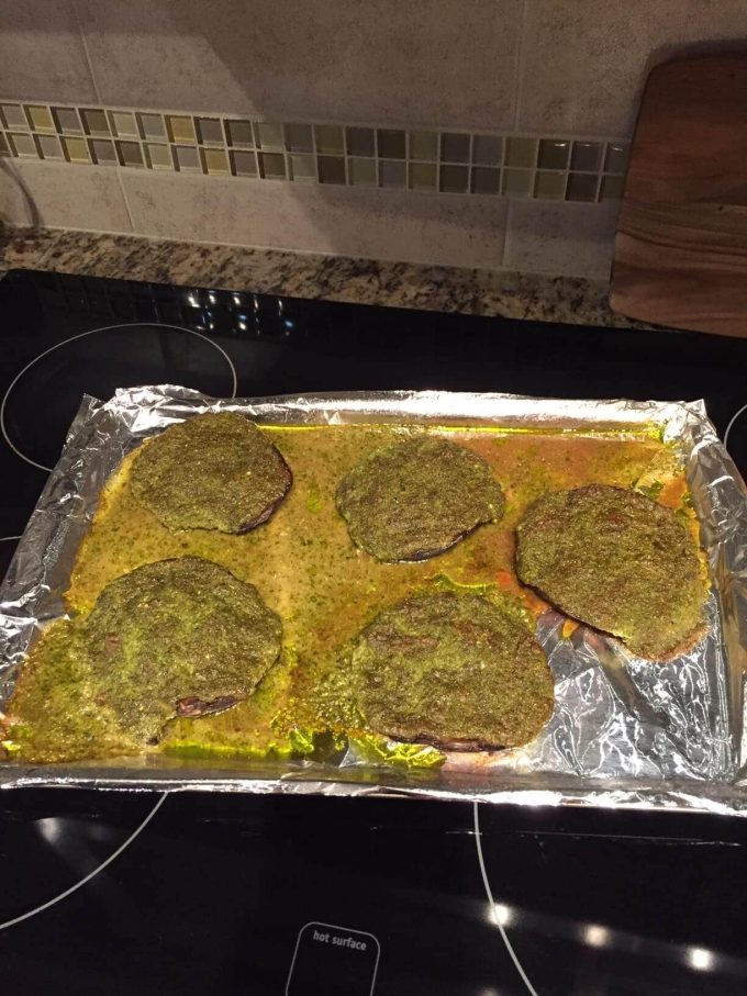 baking sheet with five pesto stuffed portobello mushrooms looking like a disaster