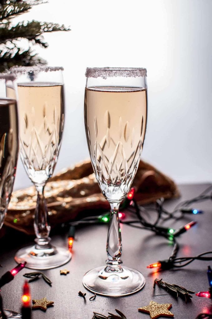 three glasses of champagne pear cocktail beside holiday lights