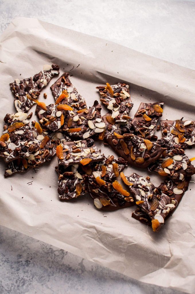 several pieces of fruit and nut chocolate bark on parchment paper
