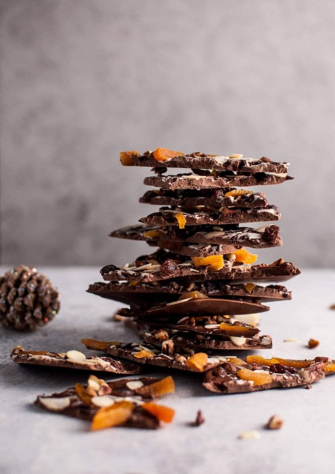 large stack of fruit and nut chocolate bark next to a pine cone