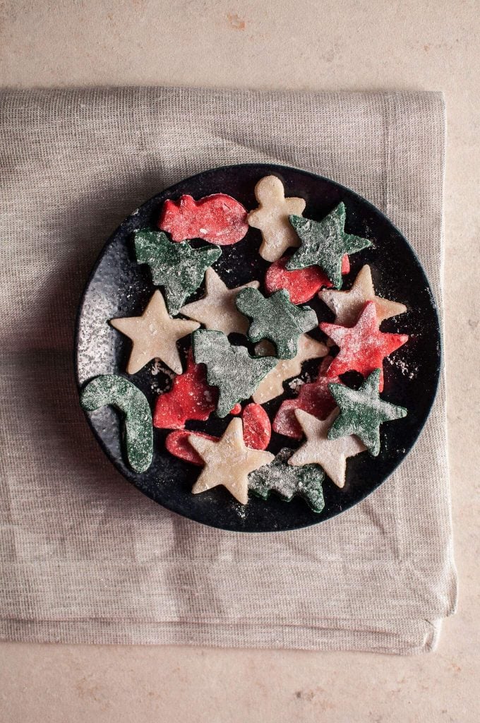 plate of homemade marzipan holiday treats in different festive shapes like Christmas trees, stars, and candy canes