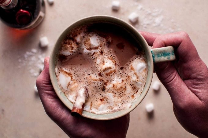 hands holding a mug of spiked boozy orange hot chocolate