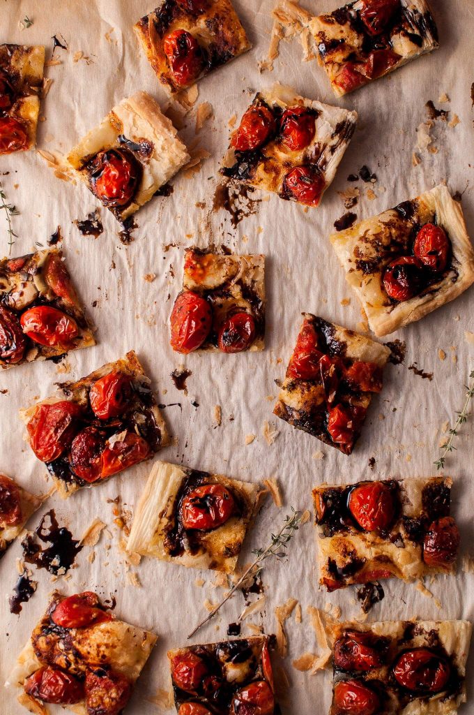 several vegetarian puff pastry roasted tomato appetizer slices with balsamic drizzle