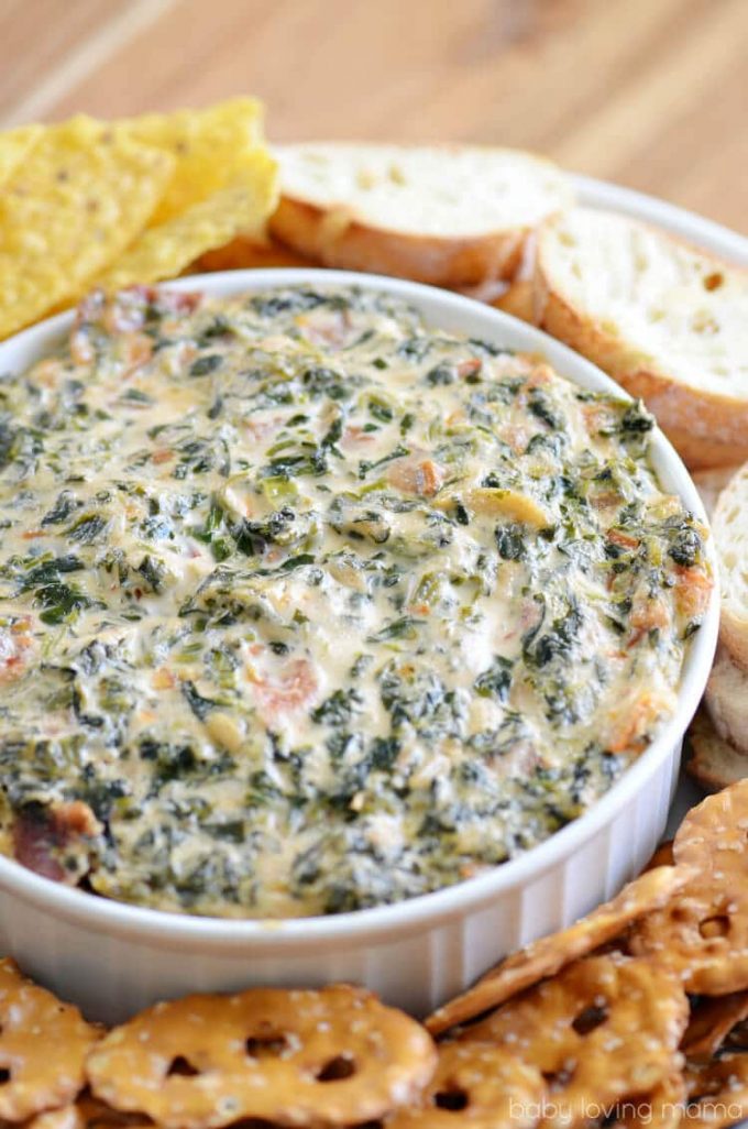 hot bacon spinach dip in a bowl beside bread and crackers