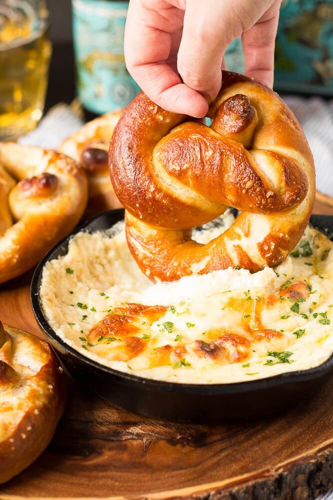 hand dipping a soft pretzel into dip