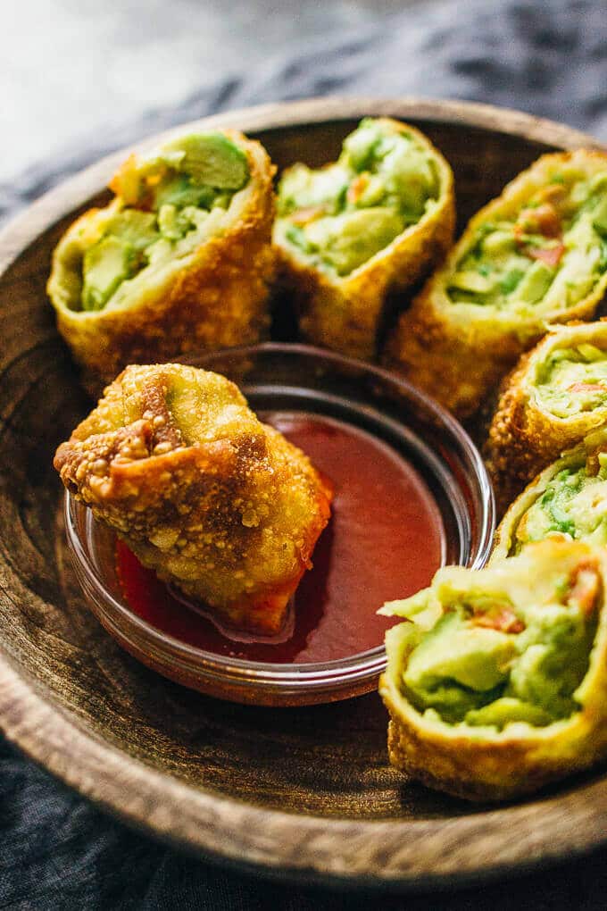 close-up of avocado egg rolls in a bowl with sweet chili dip