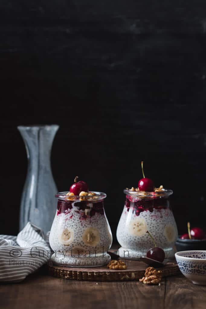 creamy chia seed breakfast pudding in two glasses topped with cherries