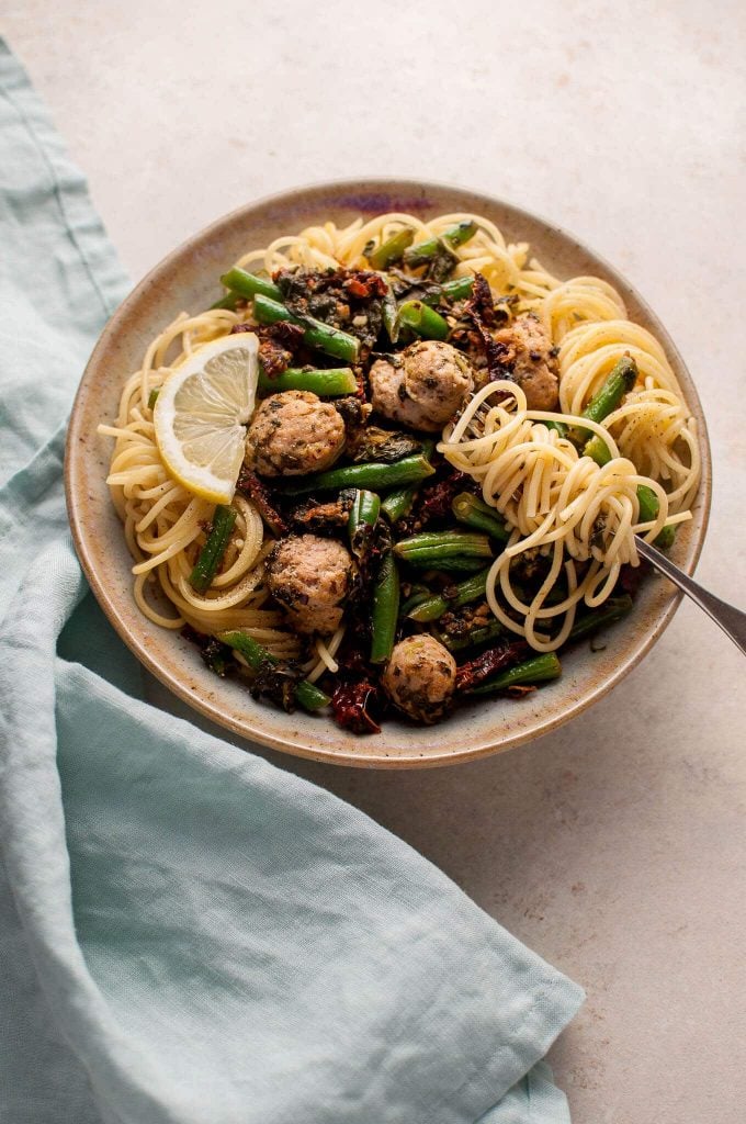 bowl of healthy chicken sausage spaghetti with spinach, lemon, and green beans and a fork