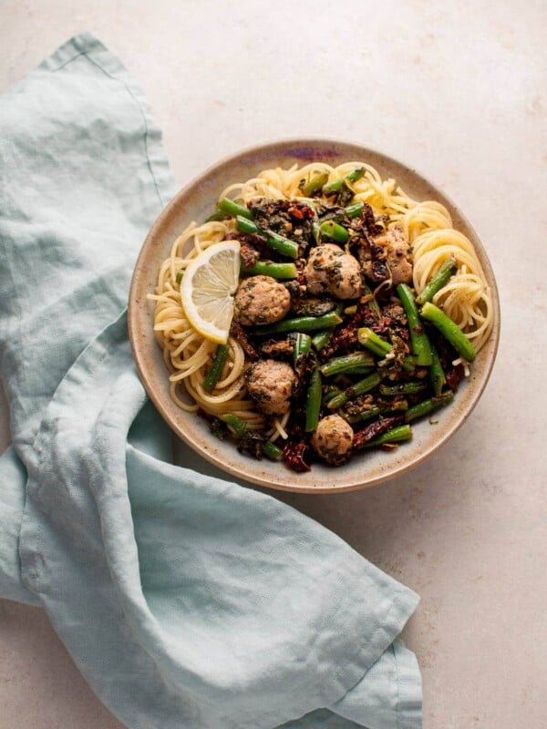 bowl of healthy chicken, sausage, and green beans pasta next to a cloth napkin