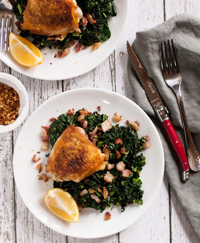 crispy chicken thighs with garlicky kale on a plate with knife and fork