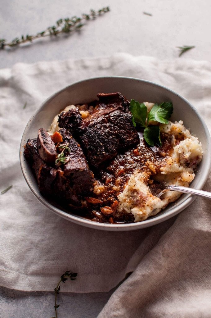 Crockpot red wine braised short ribs in a bowl with mashed potatoes and a fork