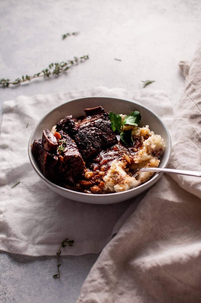 slow cooker short ribs braised in red wine in a bowl with mashed potatoes and a fork