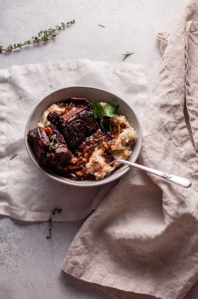 bowl of Crockpot red wine braised short ribs with a fork beside a cloth napkin