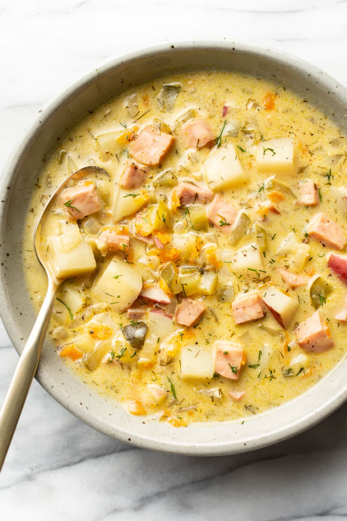 a bowl of dill pickle soup with a spoon