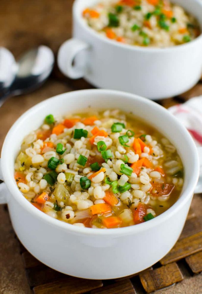 healthy barley soup with carrots in a white bowl