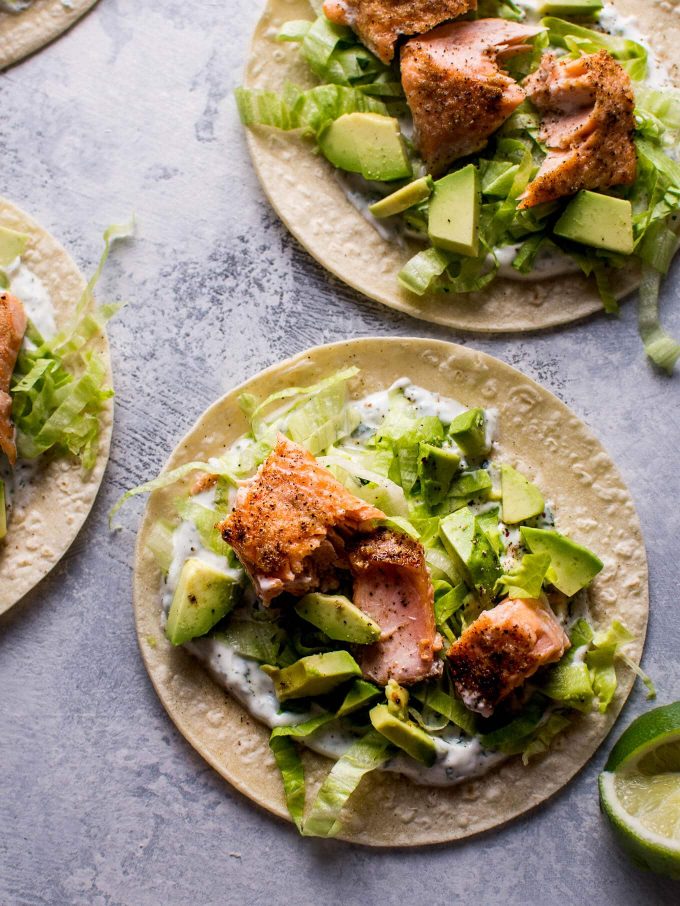 two healthy baked salmon tacos topped with avocado and cilantro lime Greek yogurt dressing
