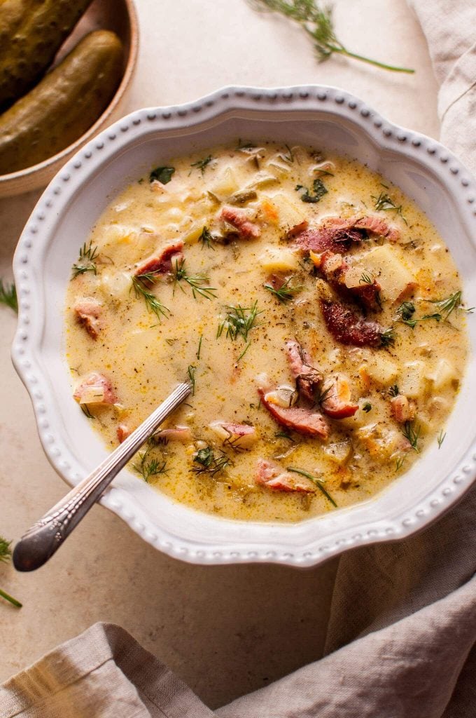 bowl of Polish dill pickle, potato, carrot, and smoked ham soup with a spoon