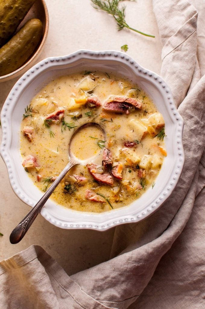 bowl of Polish dill pickle soup with smoked ham and a spoon