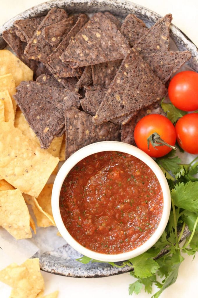 restaurant-style salsa in a white dish beside tortilla chips and little tomatoes