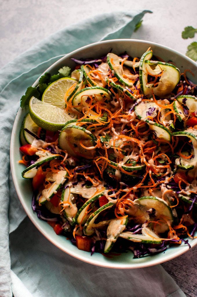 close-up of a bowl of spiralized vegetable Thai salad with slices of lime