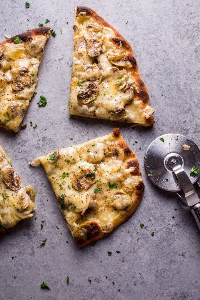 slices of vegetarian truffled mushroom naan pizza beside a pizza slicer