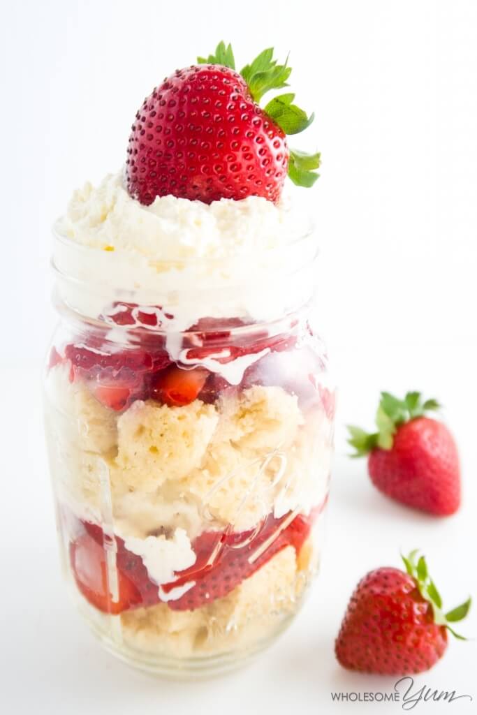 close-up of strawberry shortcake in a jar beside whole strawberries