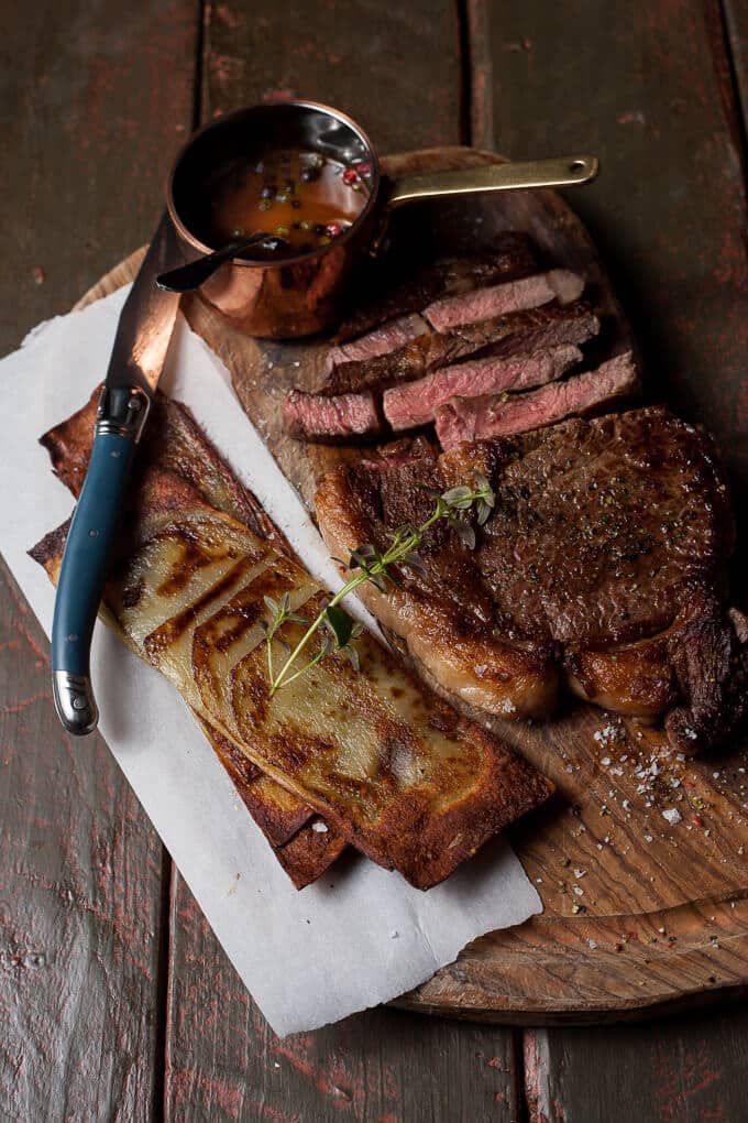 sirloin with peppercorn whiskey sauce and a knife on a wooden cutting board