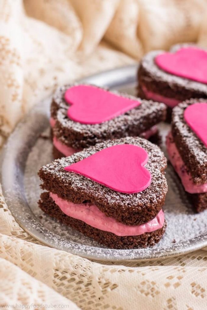 four mini chocolate cake hearts on a plate with icing