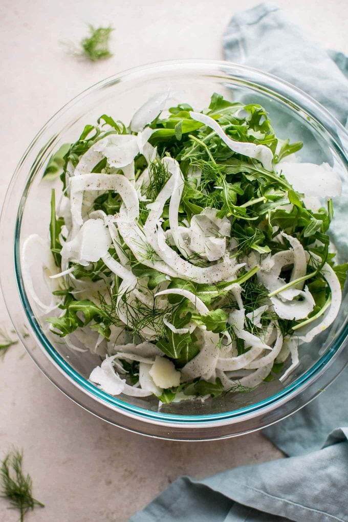 glass serving bowl with arugula, fennel, and Manchego cheese salad