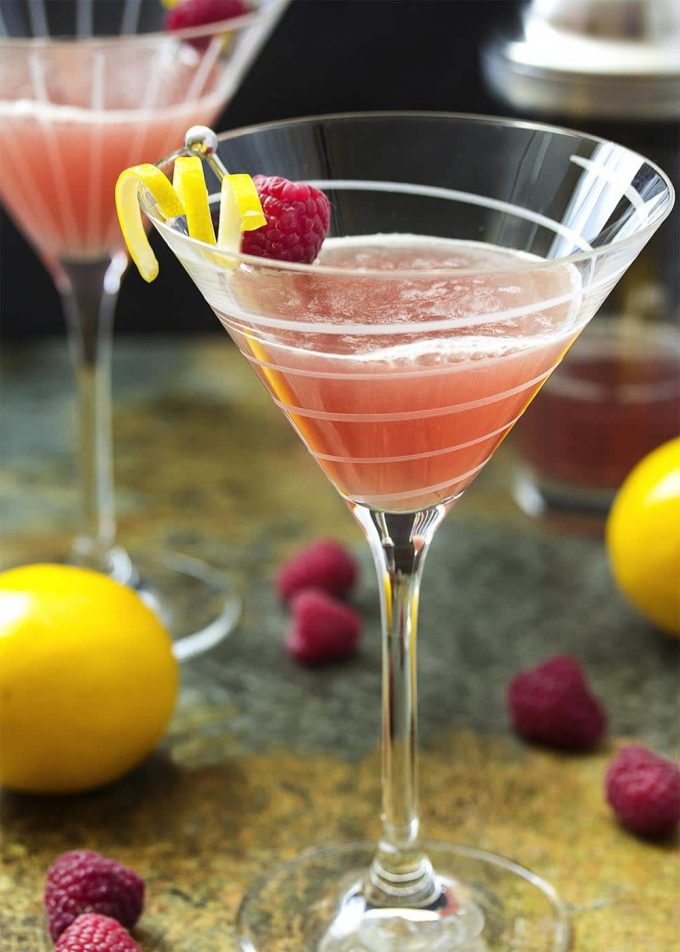 close-up of lemon drop martini in a glass garnished with lemon and a raspberry