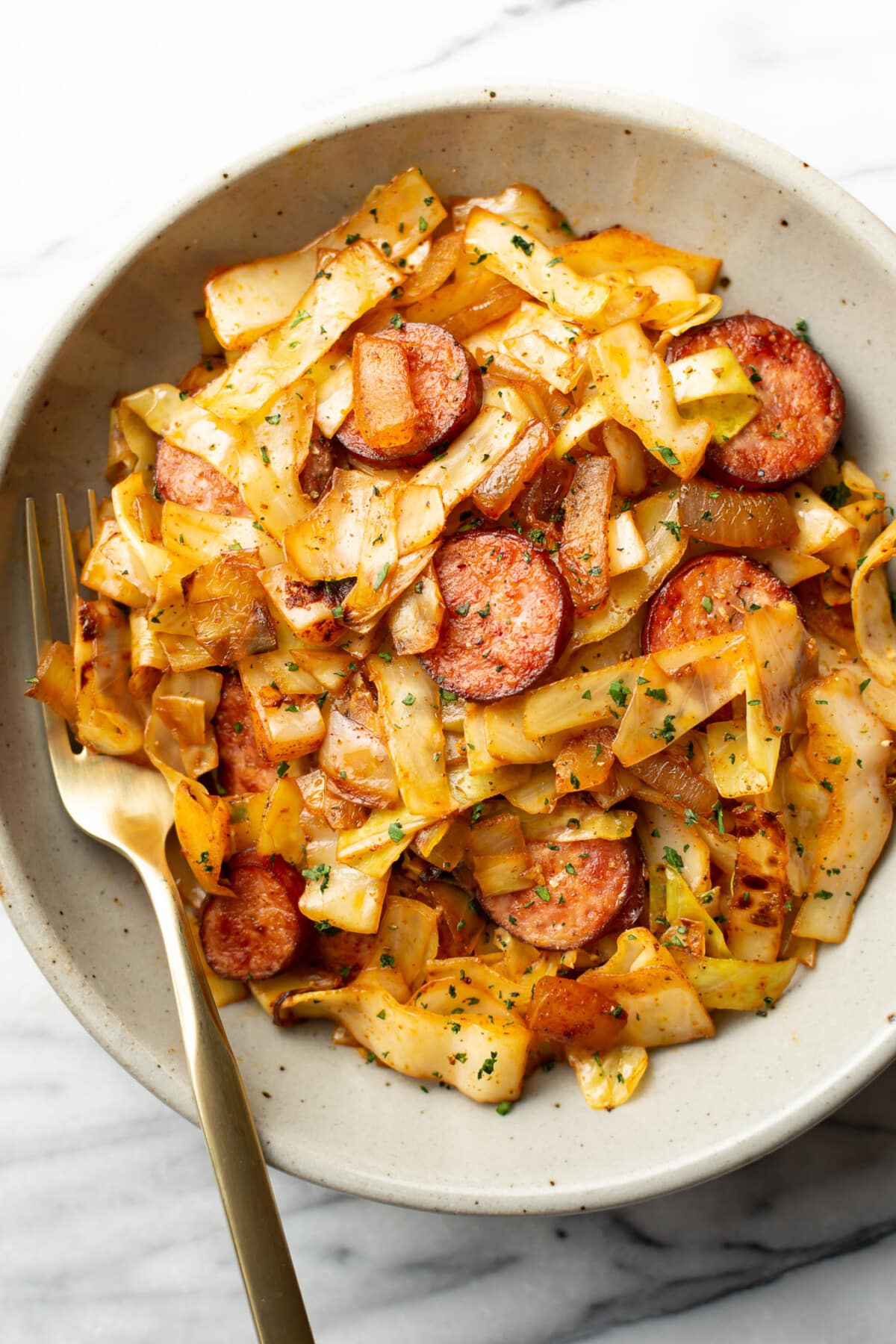 a bowl of sauteed cabbage and kielbasa with a fork