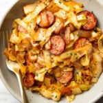 a bowl of sauteed cabbage and kielbasa with a fork