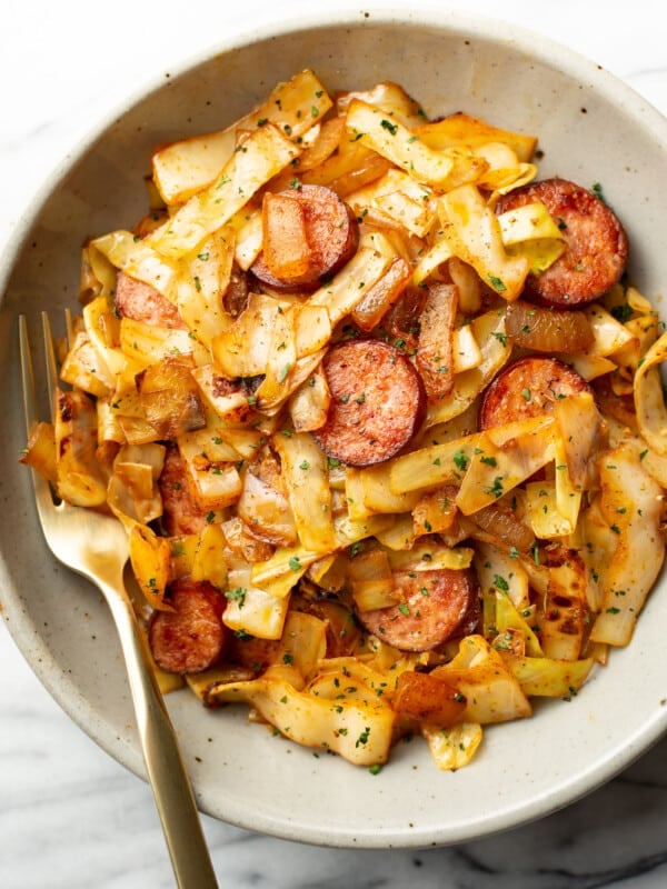 a bowl of sauteed cabbage and kielbasa with a fork
